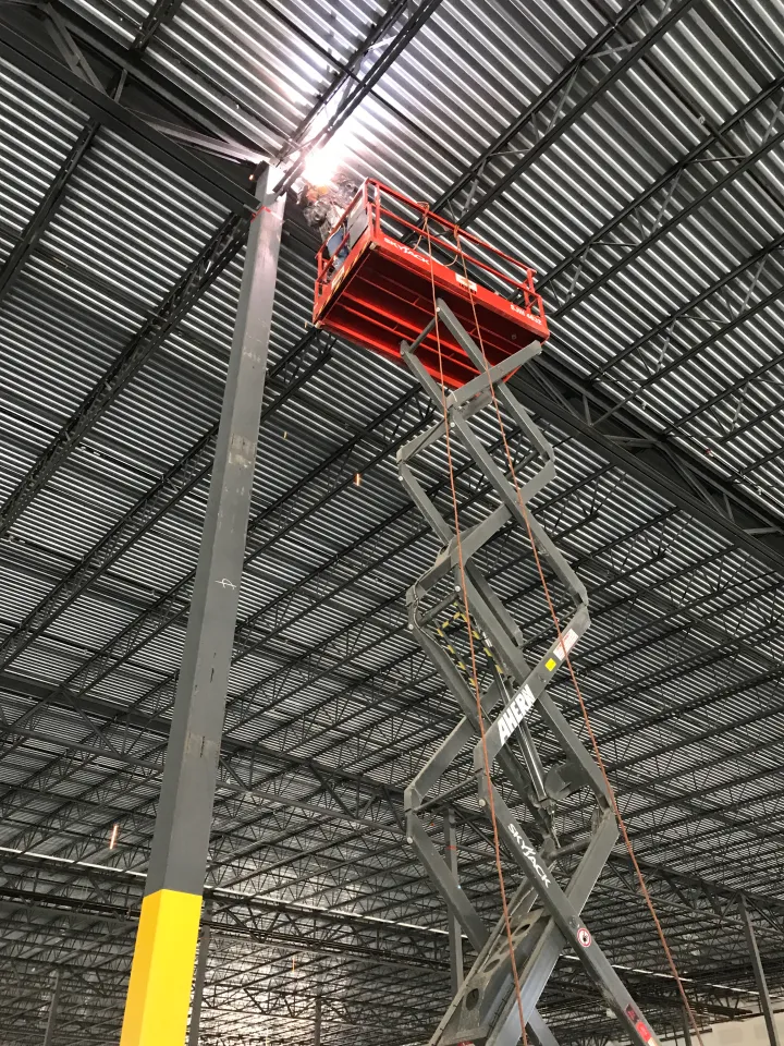 Larry's Mobile Welding working from a scissor lift on structural steel